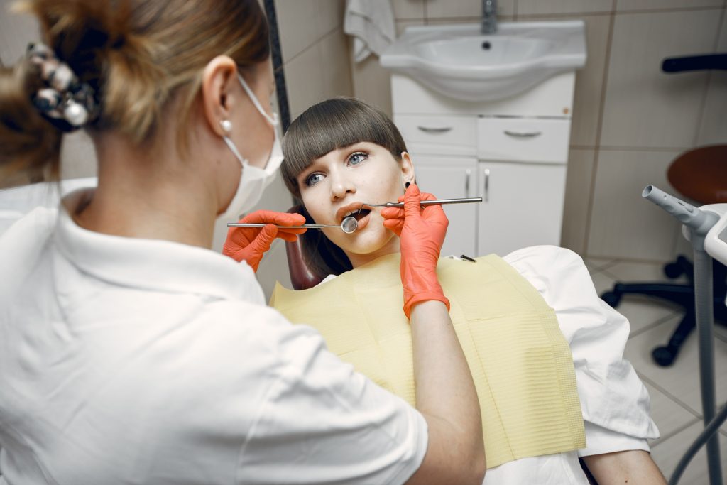 Medic stomatolog verificând o fațetă dentară desprinsă